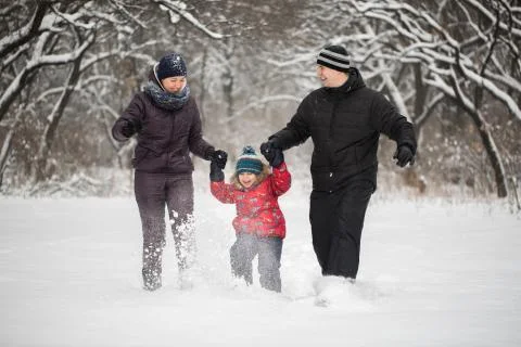 Happy family running on snow in winter. Stock Photos