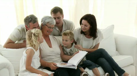 Happy Family sitting on sofa looking at a Photo Album at home Stock Footage
