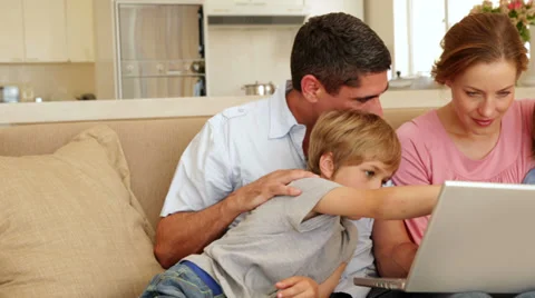 Happy family sitting on the sofa using laptop together Stock Footage