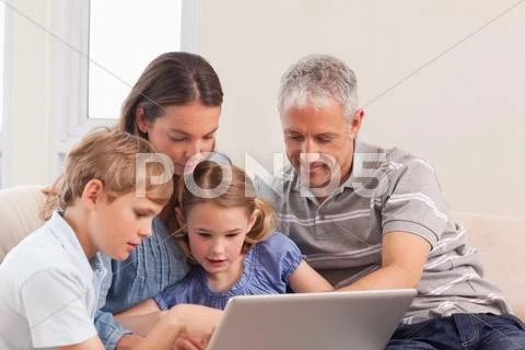 Happy family sitting on a sofa using a laptop Stock-Fotos