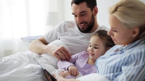 Happy family with tablet pc in bed at home Stock Footage