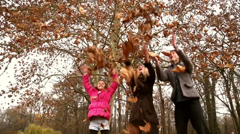 Happy family throwing leaves in the air in park Stock Footage 59554534