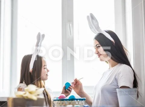 Happy family time while painting easter eggs. Mother and daughter preparing f Stock Photos