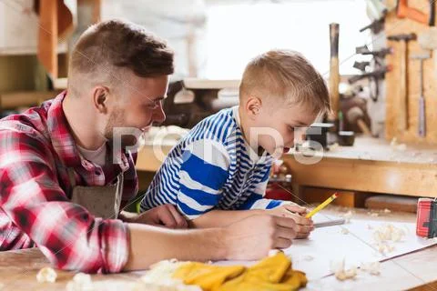 Happy father and son with blueprint at workshop Stock Photos