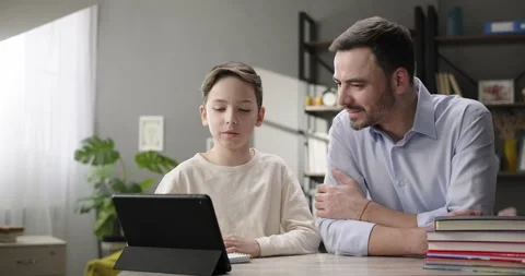 Happy father and son doing homework at home desk, e-learning online using app or Stock Footage 269058481