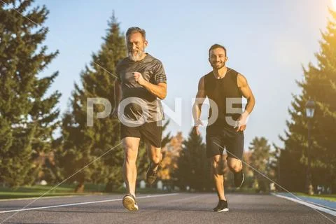 The happy father and a son running on the park road Stock Photos