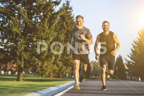 The happy father and a son running on a park road Stock Photos