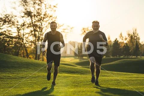 The happy father and a son running on the park grass Stock Photos