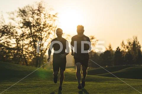 The happy father and a son running on a park grass on the sunset background Stock Photos