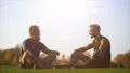 The happy father and a son sitting on the grass and talking. slow motion 4k or 4k+ Resolution
