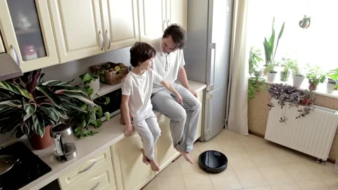 Happy Father and Son testing the Robotic Vacuum Cleaner in the Kitchen Stock Footage 163817723