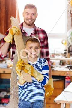 Happy father and son with wood plank at workshop Stock Photos