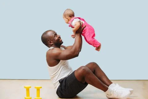 Happy father doing exercises, using his infant child as weight Stock Photos