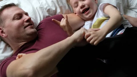 Happy father having fun on a bed with his son child, laughing. View from above Stock Footage 131174066