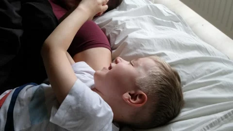 Happy father having fun on a bed with his son child, laughing. View from above Stock Footage 131174134