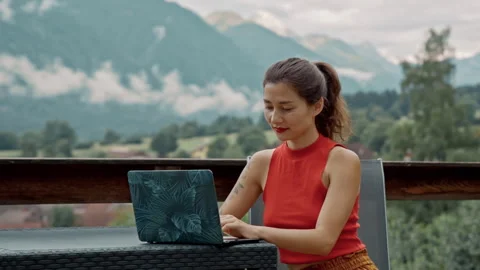 Happy female asian freelancer using laptop sitting on the roof terrace in Stock Footage 252322006