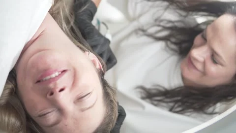 A happy female client doing a procedure for hair growth on her head on the Stock Footage 310722758