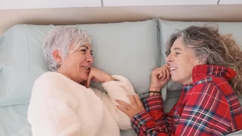 Happy female couple smiling while relaxing together on the bed at home. Stock Footage 246544495