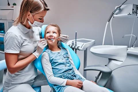 Happy female dentist with patient girl at clinic Stock Photos