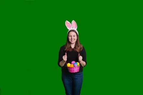 Happy female holding Easter egg basket in front of her wearing bunny ears Stock Photos