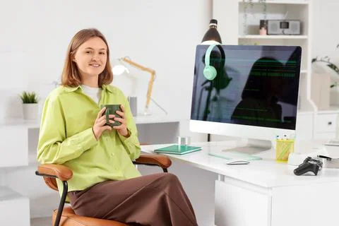 Happy female programmer with computer and cup of coffee working in office Stock Photos