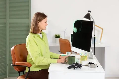 Happy female programmer with computer and cup of coffee working in office 스톡 사진