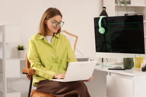 Happy female programmer with laptop, computer and cup of coffee working in of Stock Photos