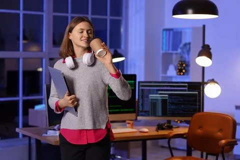 Happy female programmer with laptop, cup of coffee and headphones working in  Stock-Fotos