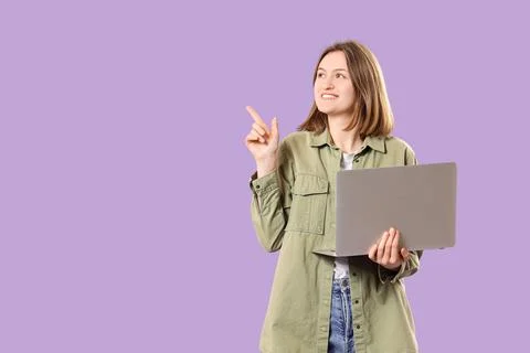Happy female programmer with laptop pointing at something on purple backgroun Stock Photos
