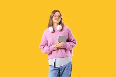 Happy female programmer with tablet and headphones on yellow background Stock Photos
