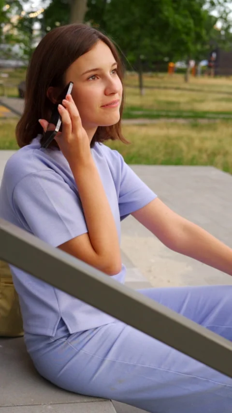 Happy female student laughing while listening to voice message on mobile phone Stock Footage 340022086