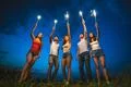The happy five people hold firework sticks. evening night time Photo