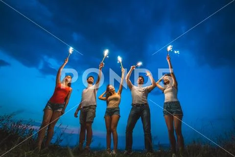 The happy five people hold firework sticks. evening night time Stock Photos
