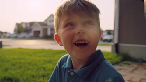 Happy five year old boy smiles at camera and looks up to reach off camera 스톡 동영상 204043480