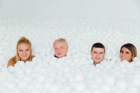 Happy Friendly family surrounded by white plastic balls in the dry pool. Stock Photos