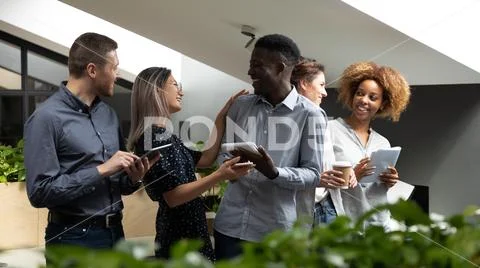 Happy friendly multiethnic business team talking laughing standing in office Stock Photos