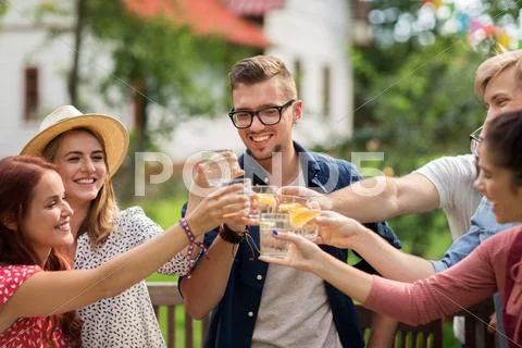 Happy friends clinking glasses at summer garden Stock Photos