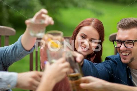 Happy friends clinking glasses at summer garden Stock Photos