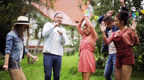 Happy friends dancing at summer party in garden Stock Footage