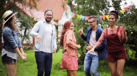 Happy friends dancing at summer party in garden Stock Footage