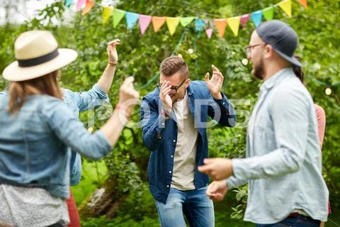 Happy friends dancing at summer party in garden Stock Photos