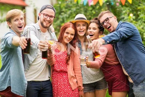 Happy friends with drinks at summer garden party Stock Photos