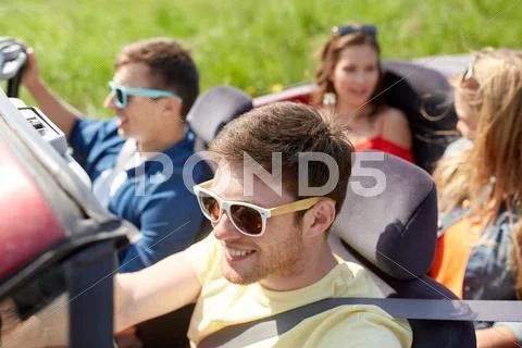 Happy friends driving in cabriolet car outdoors Stock Photos