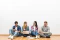The happy friends with gadgets sit on the floor on the white wall background Photo