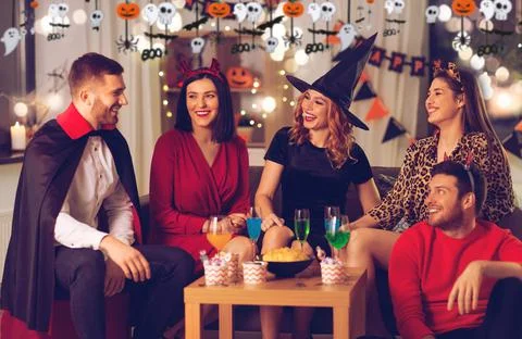 Happy friends in halloween costumes at home party Stock Photos