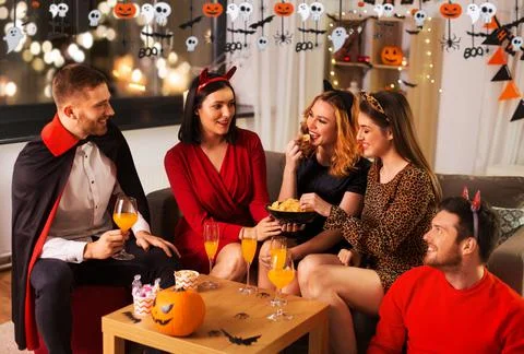 Happy friends in halloween costumes at home party Stock Photos