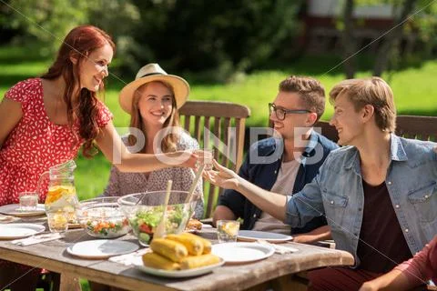 Happy friends having dinner at summer garden party Stock Photos