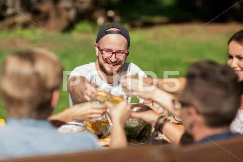 Happy friends having dinner at summer garden party Stock Photos