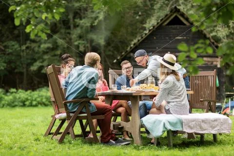 Happy friends having dinner at summer garden party Stock Photos