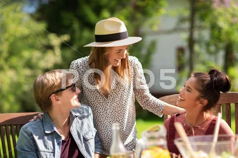Happy friends having dinner at summer garden party Stock Photos